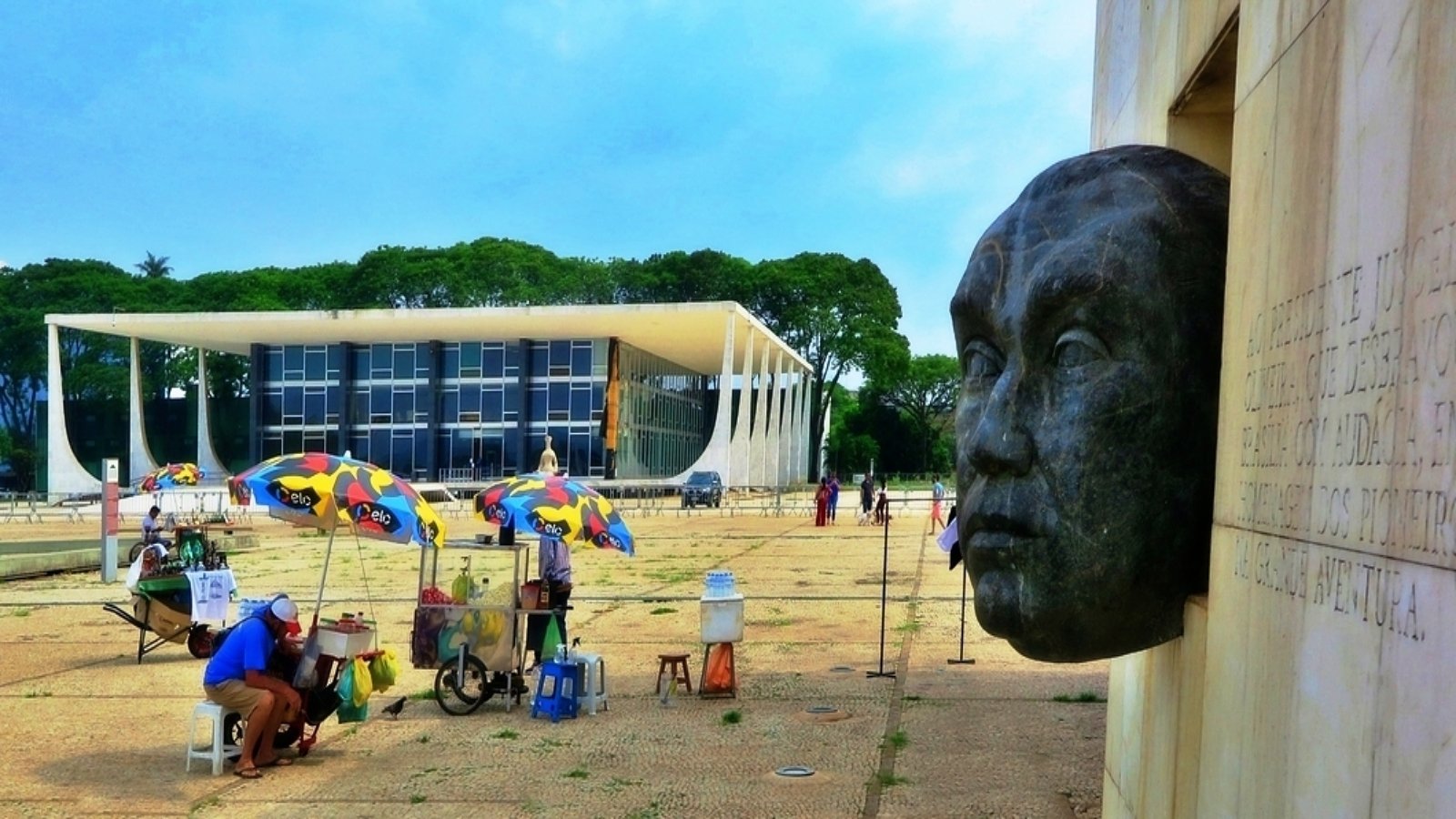 Sede do Supremo Tribunal Federal vista da Praça dos Três Poderes, em Brasília, com ambulantes e parte de um monumento em primeiro plano, foto de arquivo