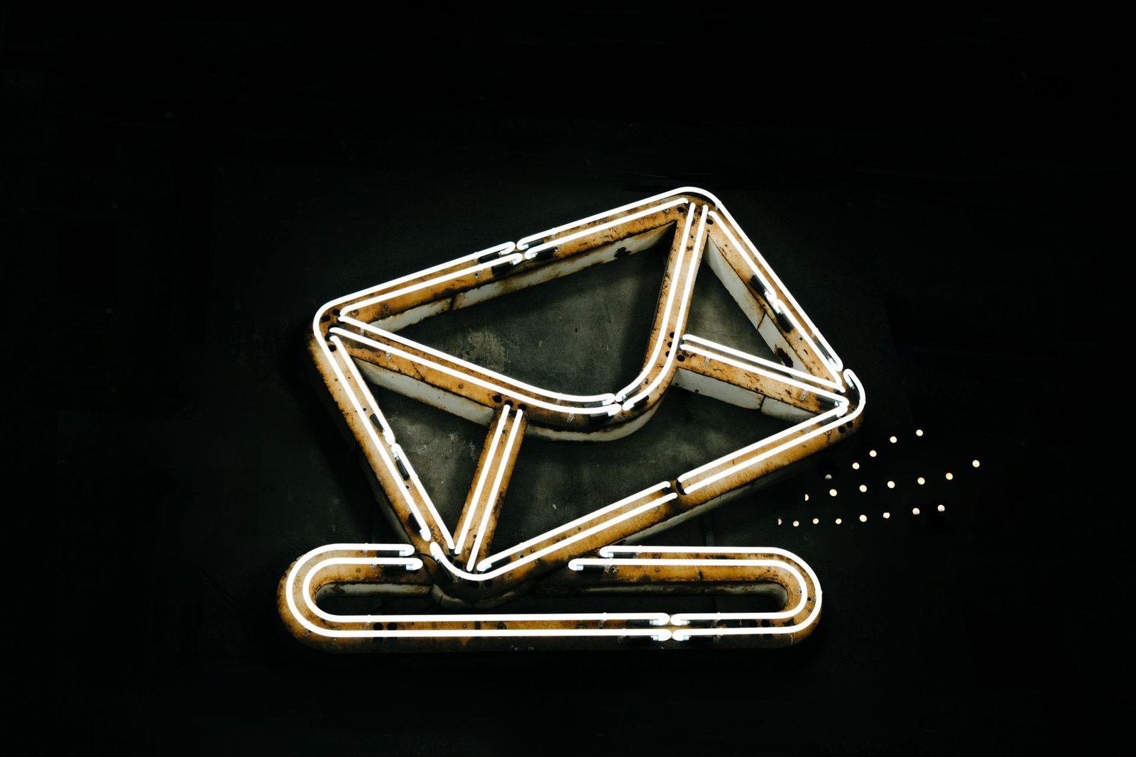 Letreiro de neon aceso no formato de um envelope de correspondência sobre fundo escuro