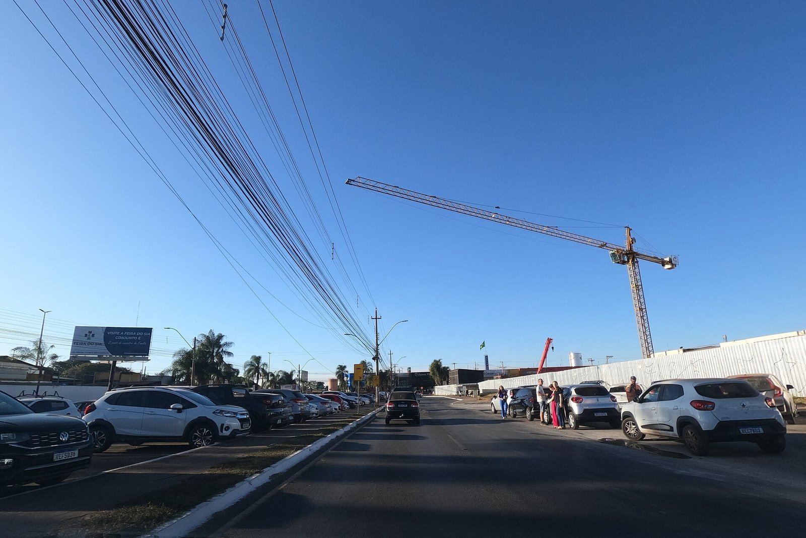 Rua do Setor de Indústria e Abastecimento (SIA), em Brasília, com carros estacionados e guindaste ao fundo