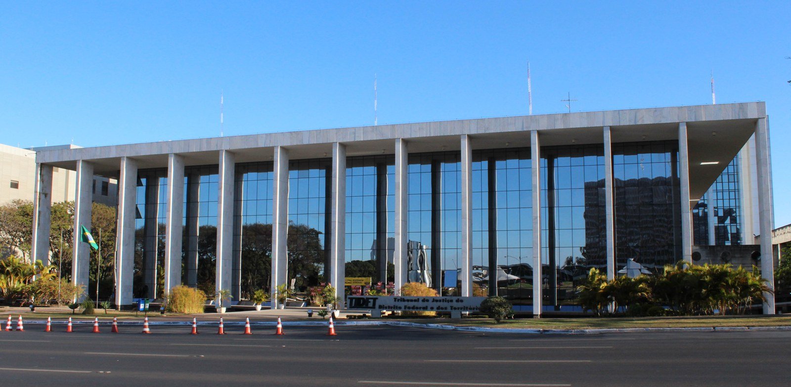 Fachada de vidro e colunas de mármore da sede do TJDFT, com a placa do tribunal à frente