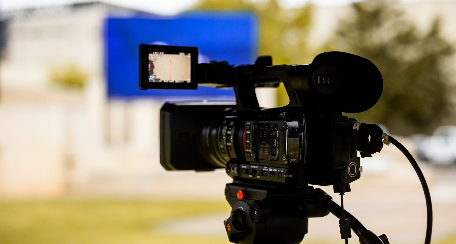 Camera de video profissional montada em tripe durante gravacao externa