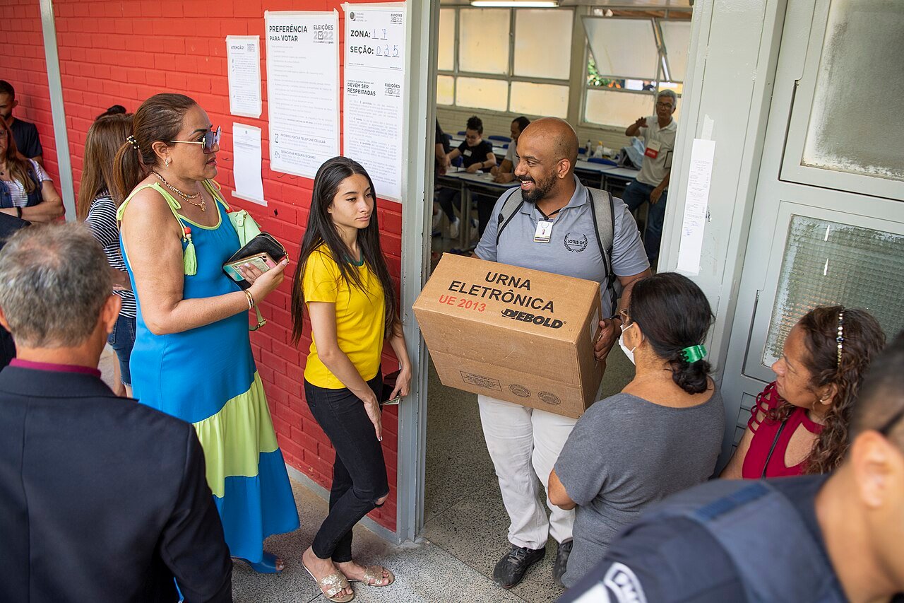 Servidor da Justiça Eleitoral carrega caixa de urna eletrônica na entrada de uma escola no DF, no segundo turno de 2022 (foto de arquivo)