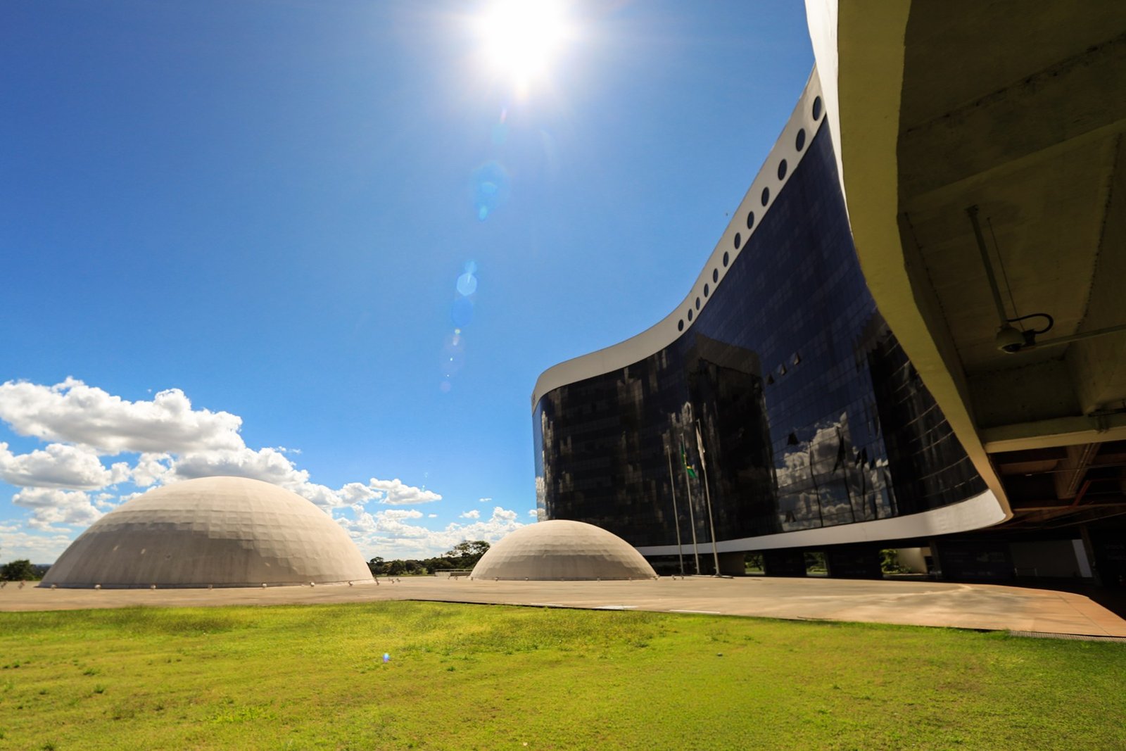 Fachada curva de vidro da sede do TSE em Brasília, com as duas cúpulas de concreto à esquerda