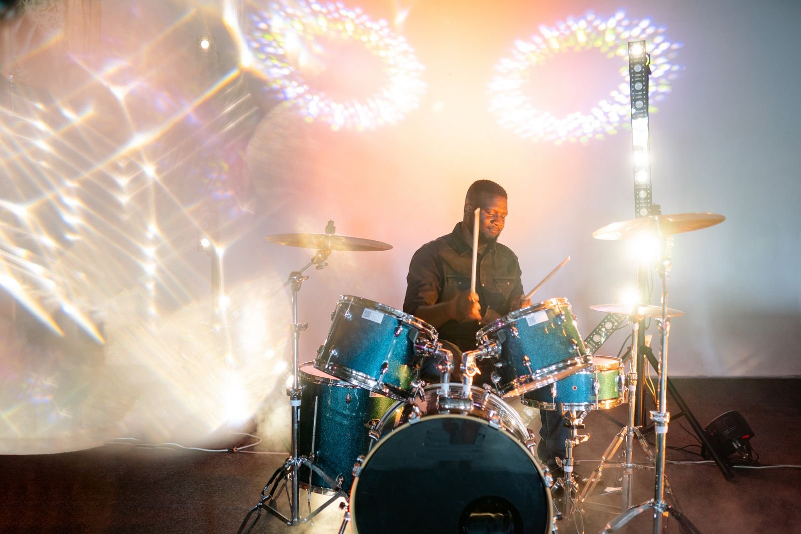 Baterista toca em palco com luzes coloridas durante show