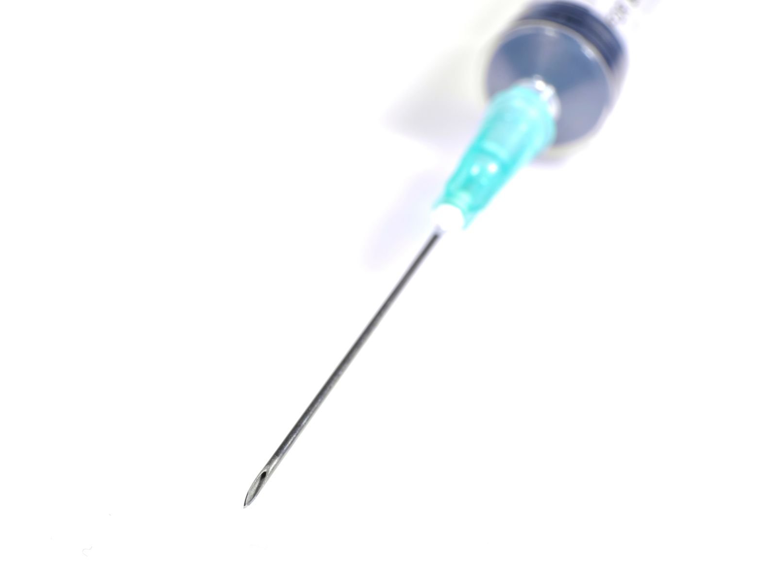 Close de agulha de seringa sobre fundo branco, imagem ilustrativa de vacinação
