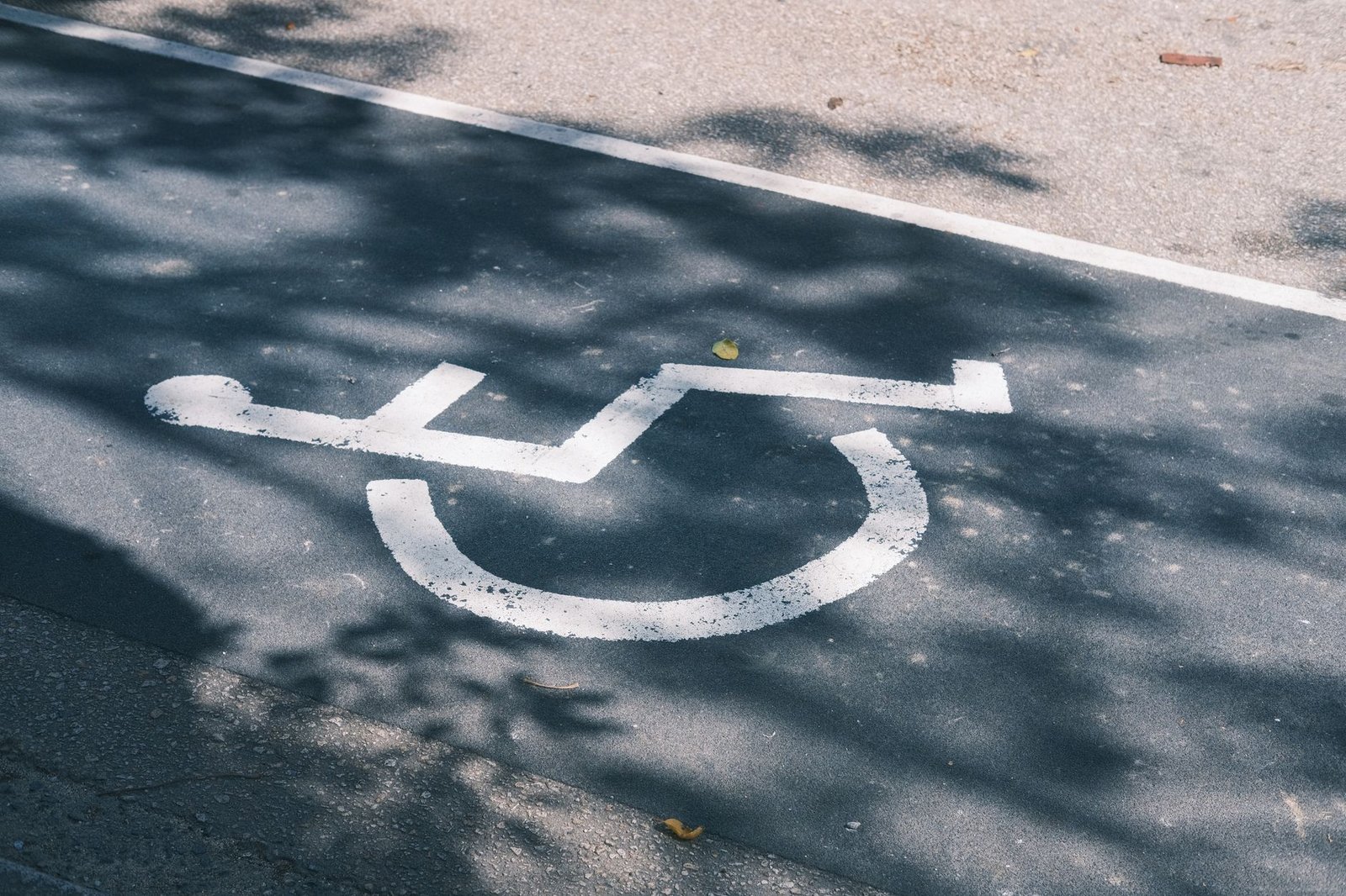Símbolo de cadeira de rodas pintado em branco no asfalto de uma vaga de estacionamento