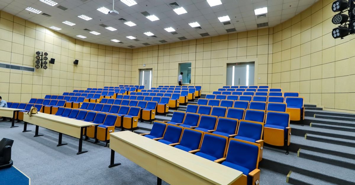 Auditório universitário vazio com fileiras de cadeiras e bancadas